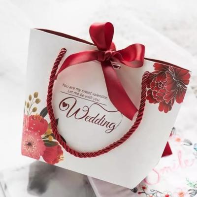 China Bolsas de papel impresas con logotipo personalizado, bolsas de regalo de boda de lujo con cierre de cinta en venta