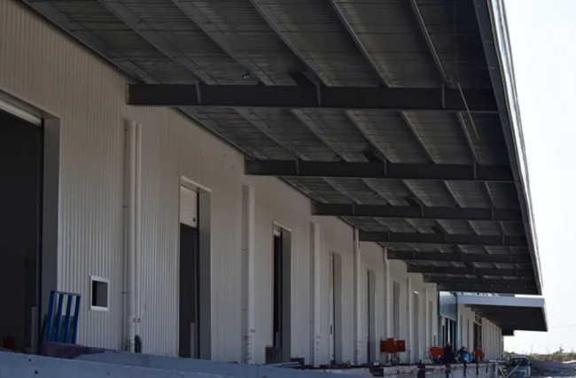 Completed steel structure logistics warehouse with large canopy and roller doors