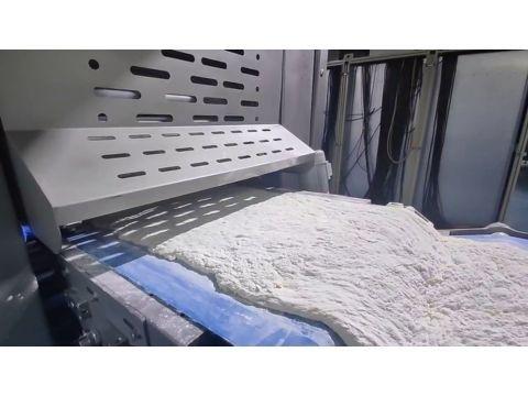 Continuous high-hydration dough band showing a smooth, glossy texture and wet surface after passing the sheeting rollers.