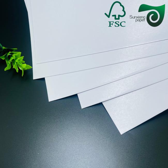Stack of glossy coated art book paper sheets demonstrating thickness and uniformity
