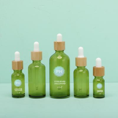 China Botella de cristal verde 15ml 20ml 30ml del dropper del aceite esencial del casquillo de bambú vacío del cuello en venta