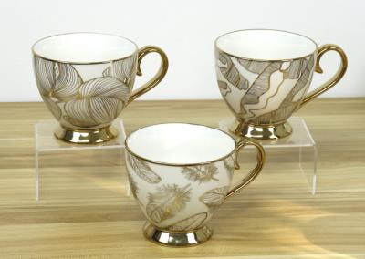 中国 New bone china footed mug with electroplating handgrip and foot for home/office use ceramic designs 販売のため