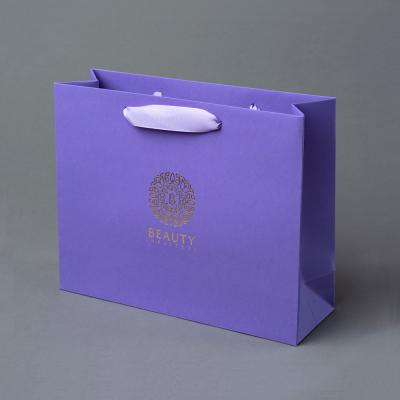 China Luxury Custom Printed Logo Embossed Purple Coated Paper Bag With Ribbon Handle for sale