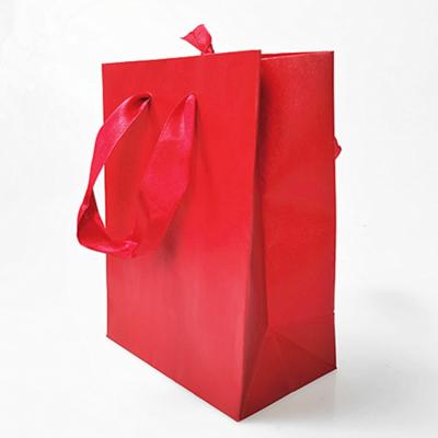 中国 リボンはレザー・ペーパーの注文のロゴの宝石類のショッピングのための明るく赤く小さいギフト袋を扱う 販売のため