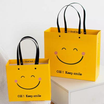 China ISO Shock Resistant Smile Face Kraft Paper Bags Yellow Square Bottom Paper Bag for sale